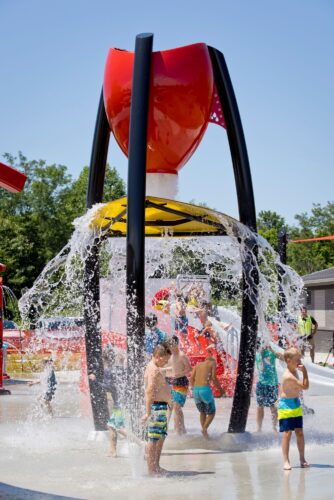 children under a water dump feature getting sprayed and laughing