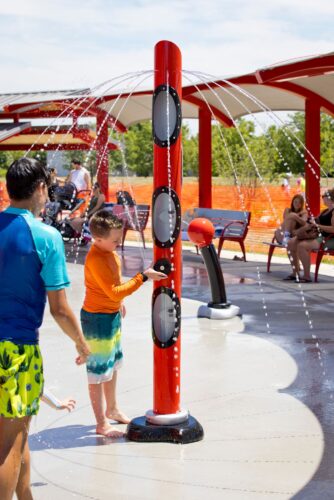 boy playing with water spraying out of multiple spots on a water pole