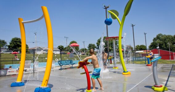 three pre-teens playing with splash pad spray equipment