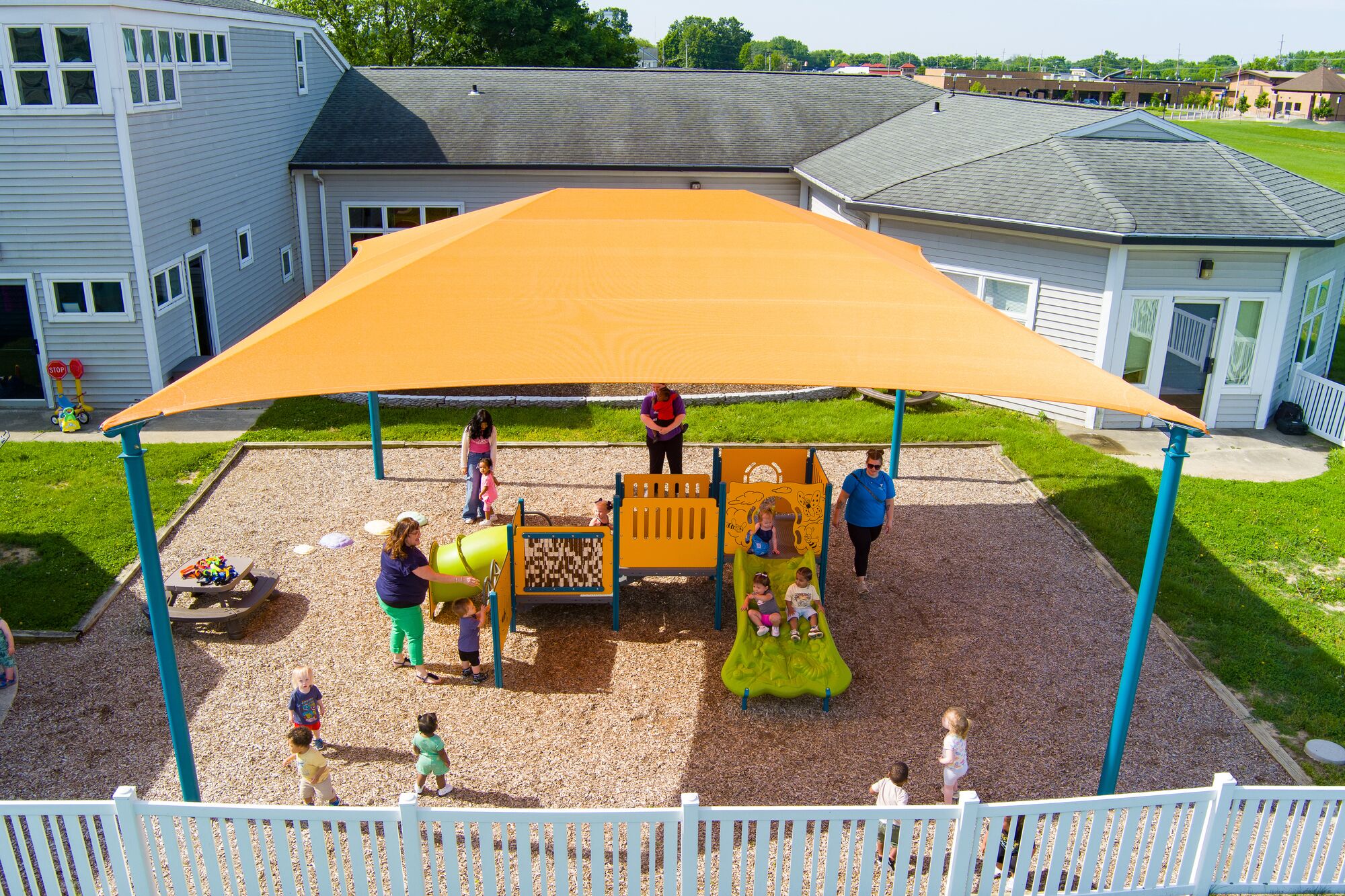 Orange, four post hip shade covering toddler playground area